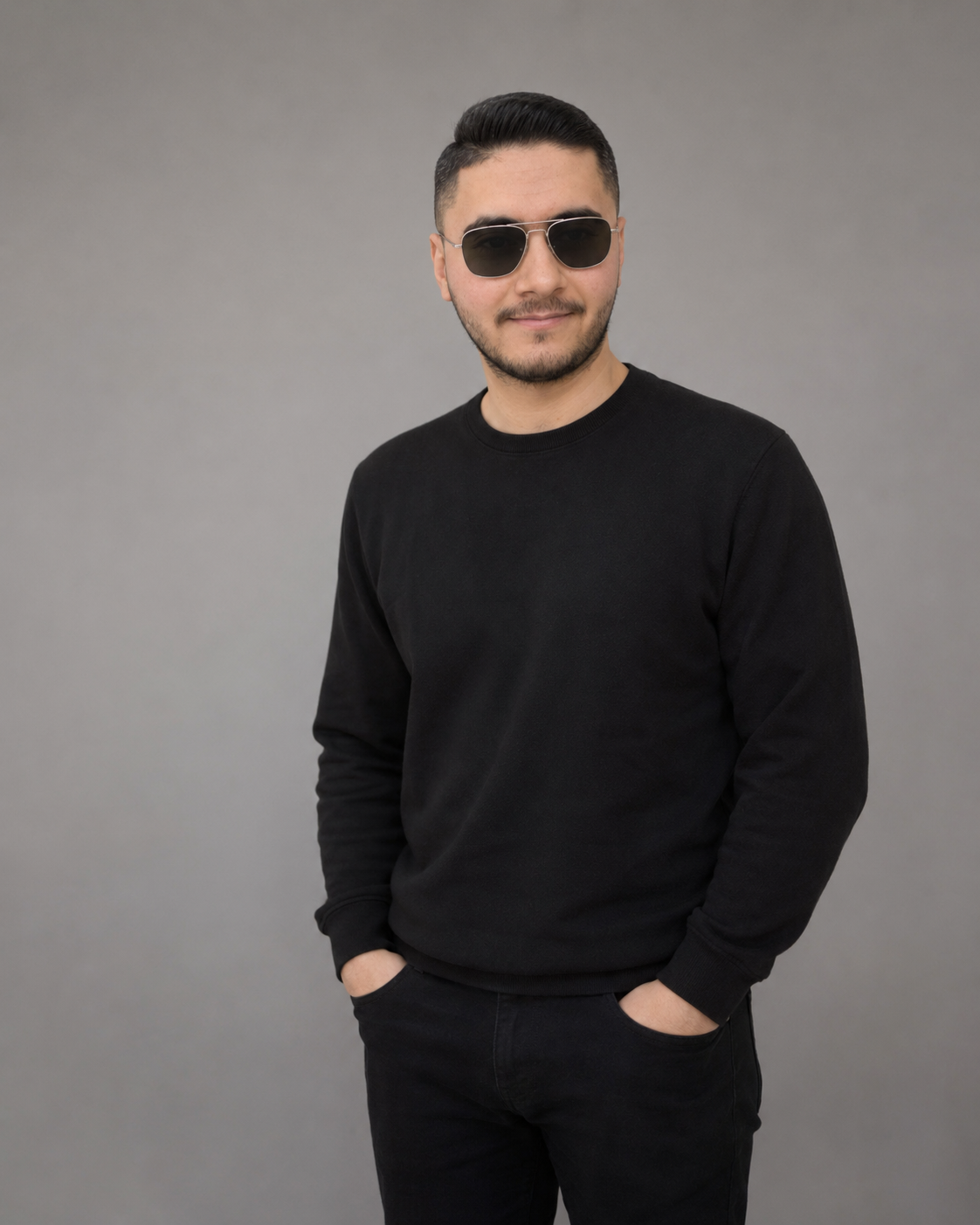 Mohamed Al-Balkhi in a black crewneck against a warm grey background